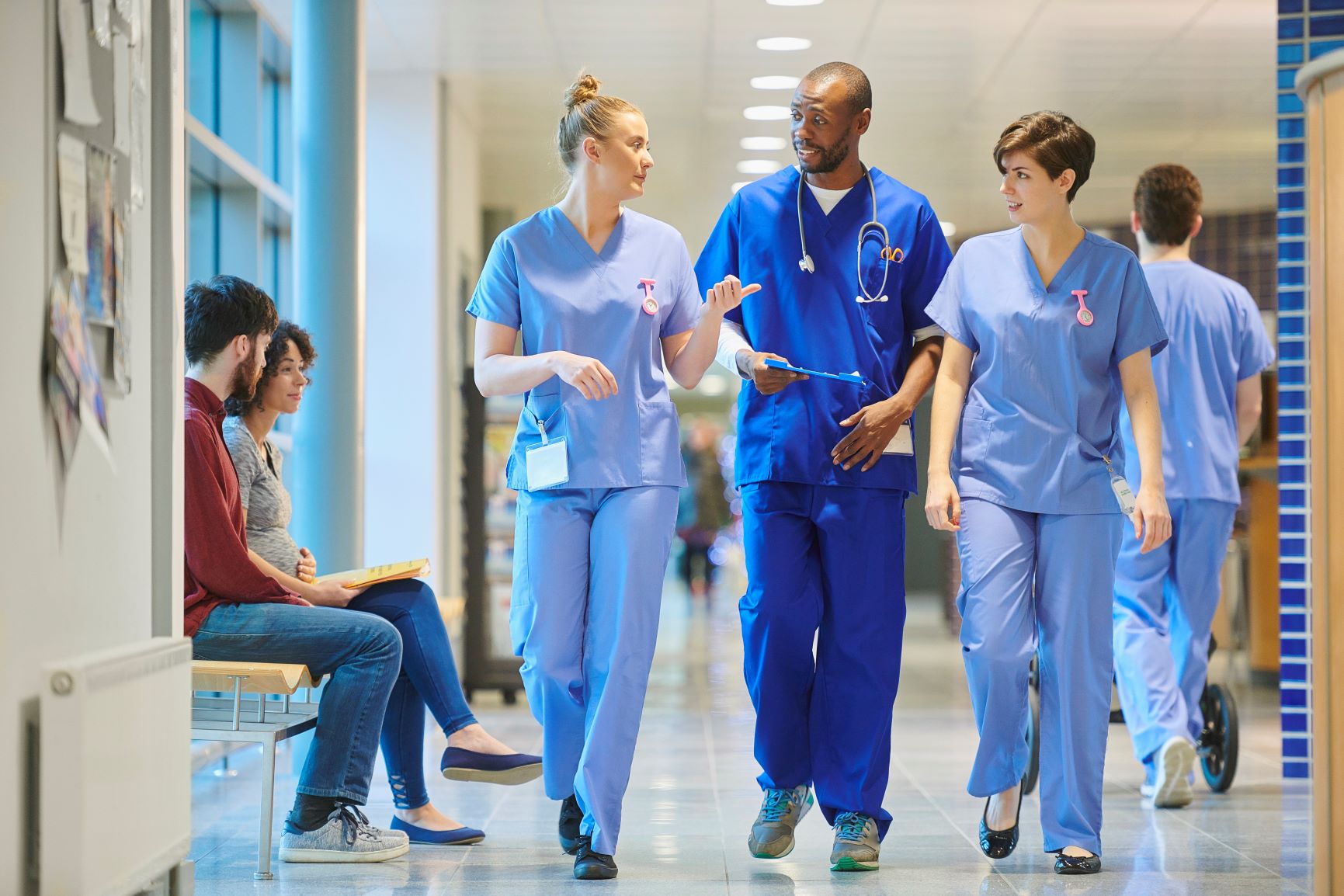 a medical consultant with two nurses walk along a hospital corridor