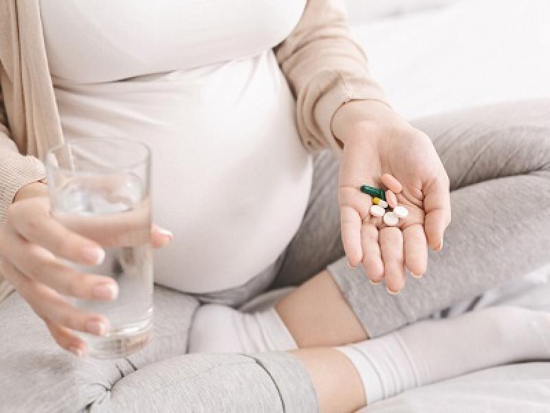 Pregnant women holding medicines and glass of water